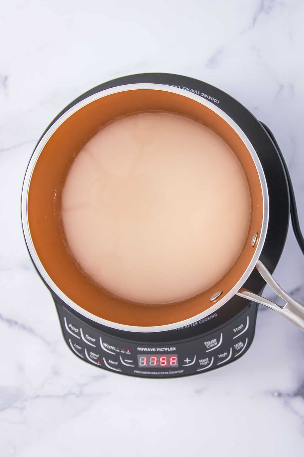 mixture of white sugar and water in a saucepan on an induction cooktop
