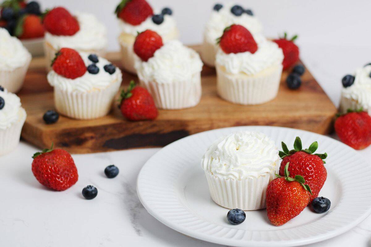 angel food cake cupcakes with whipped cream topping all displayed with fruit 