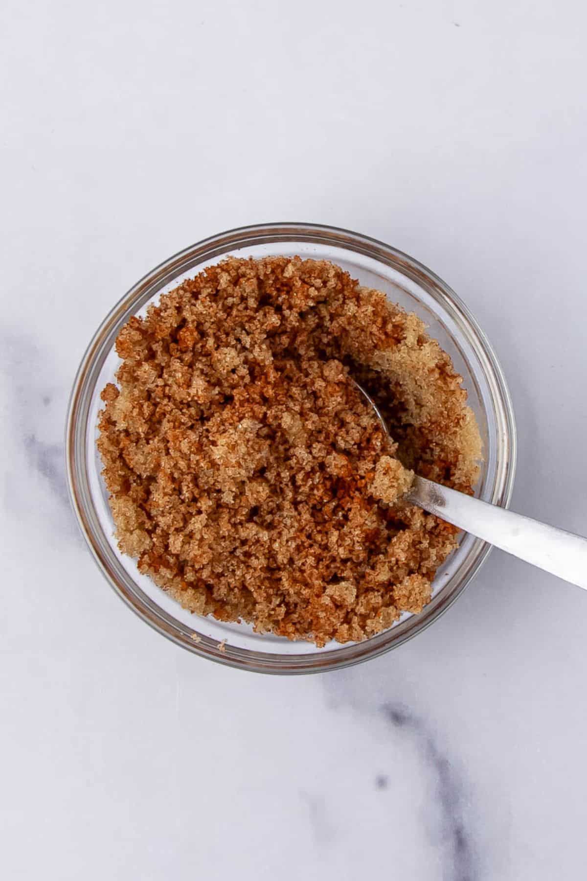 A bowl of brown sugar with a spoon inside, likely for seasoning or topping.