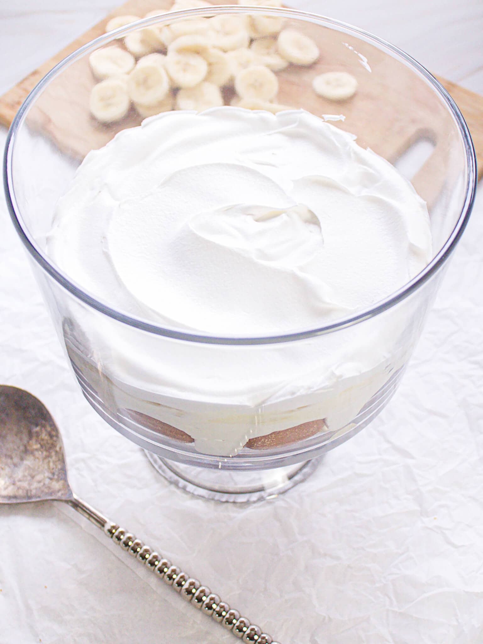 Layered banana pudding with whipped topping in a glass bowl.
