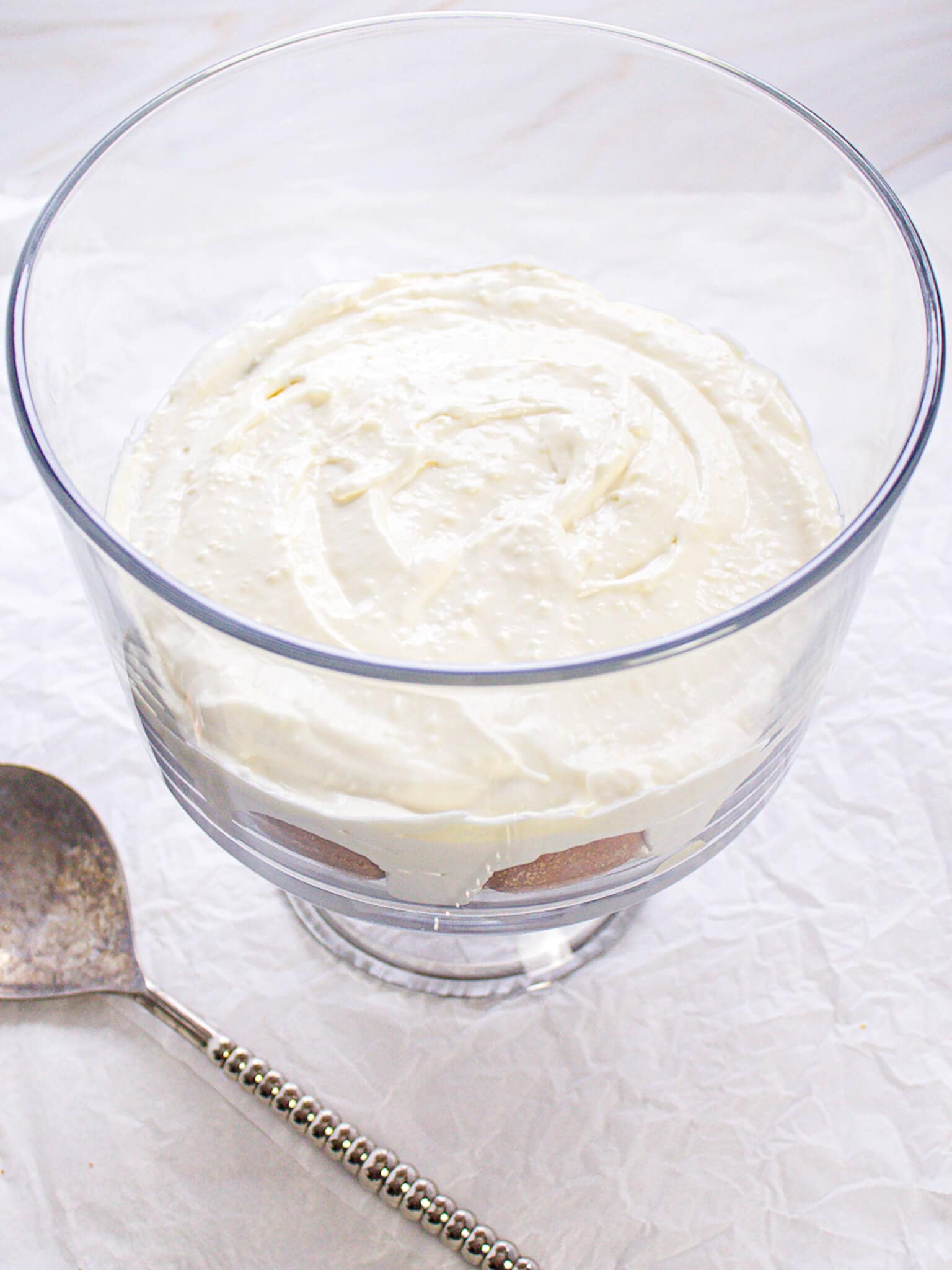 A glass trifle dish with a layer of vanilla wafers and creamy pudding mixture.