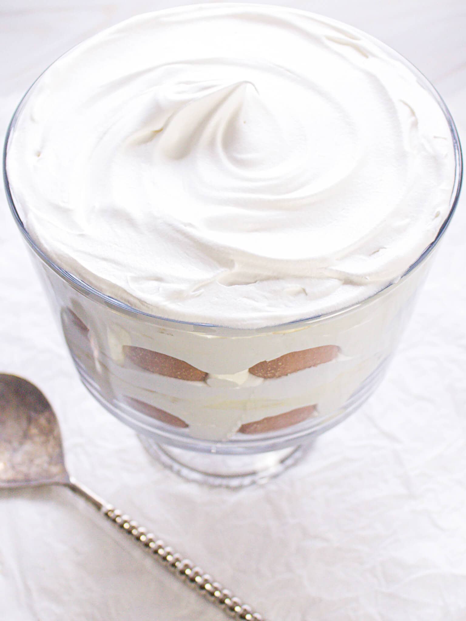 A banana pudding trifle with a smooth layer of whipped topping, neatly covering the layered dessert.