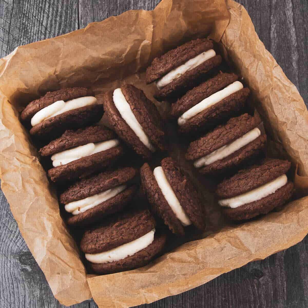 Whoopie pies with a thick layer of cream cheese filling and neatly arranged in a parchment-lined box.