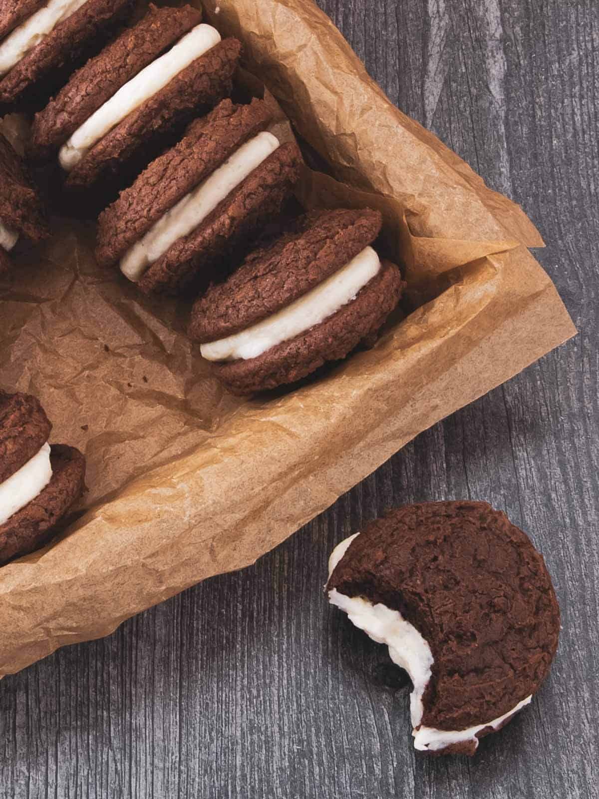 One cookie sandwich with a bite taken out, showing the soft brownie layers and creamy filling.