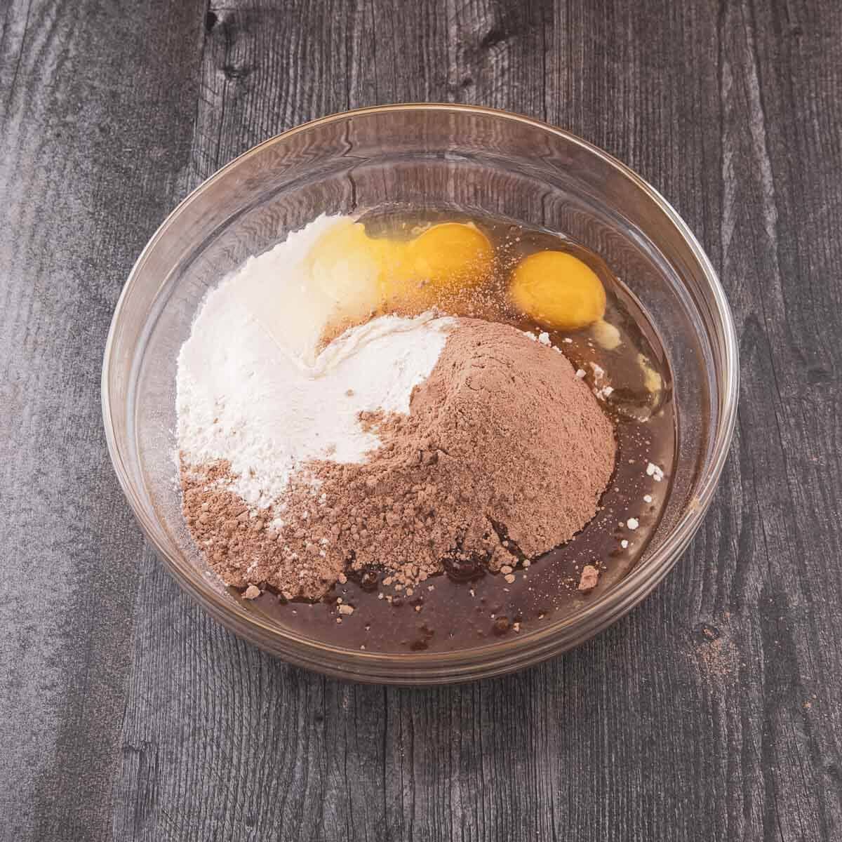 Eggs, flour, and oil combined with the brownie mix in a bowl.