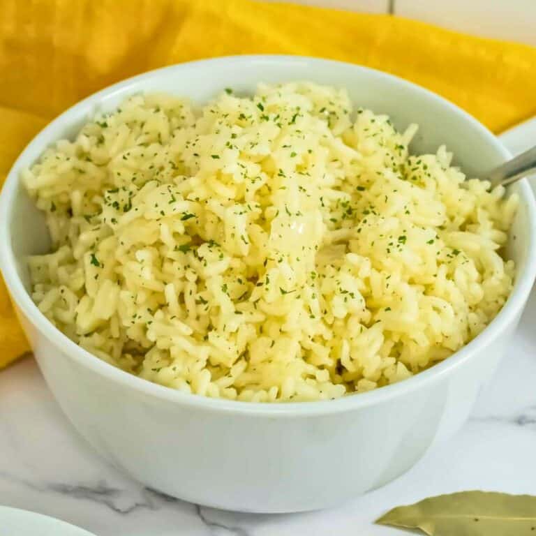 Butter rice in a bowl made with white rice, butter, onions, chicken bullion and bay leaf.