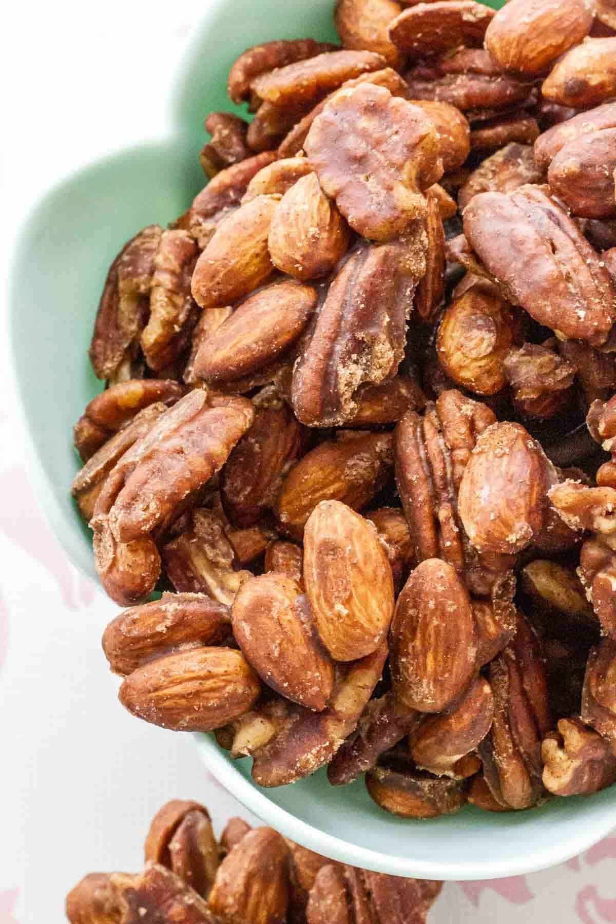 A detailed view of the crunchy, sugar-coated candied pecans and almonds in a light blue bowl