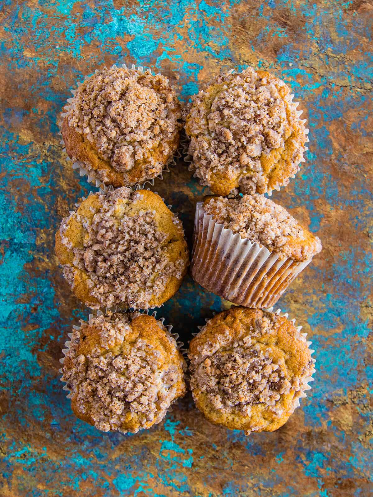 A top-down view of six muffins with a golden brown crumb topping.