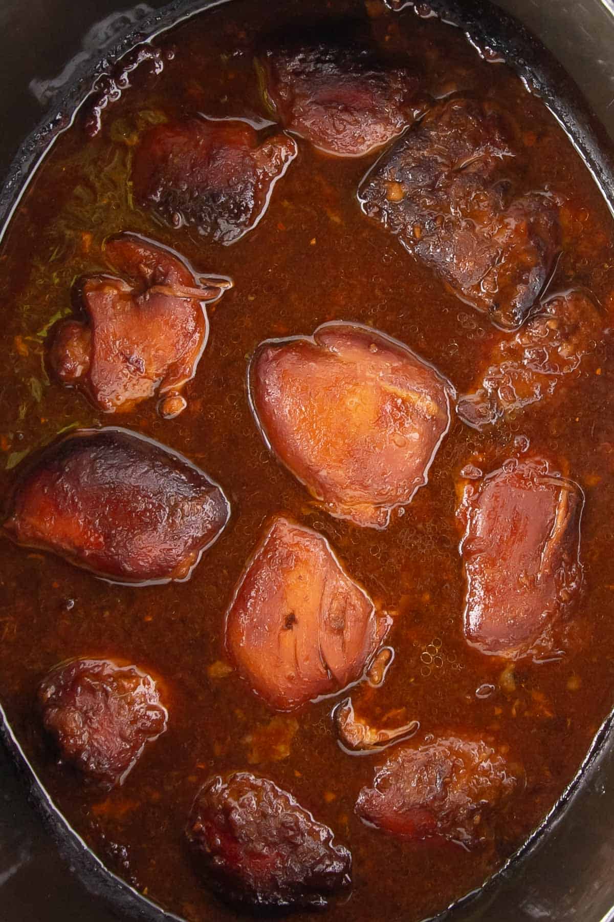 Chicken thighs fully cooked in the slow cooker, darkened and glazed in a rich apricot sauce