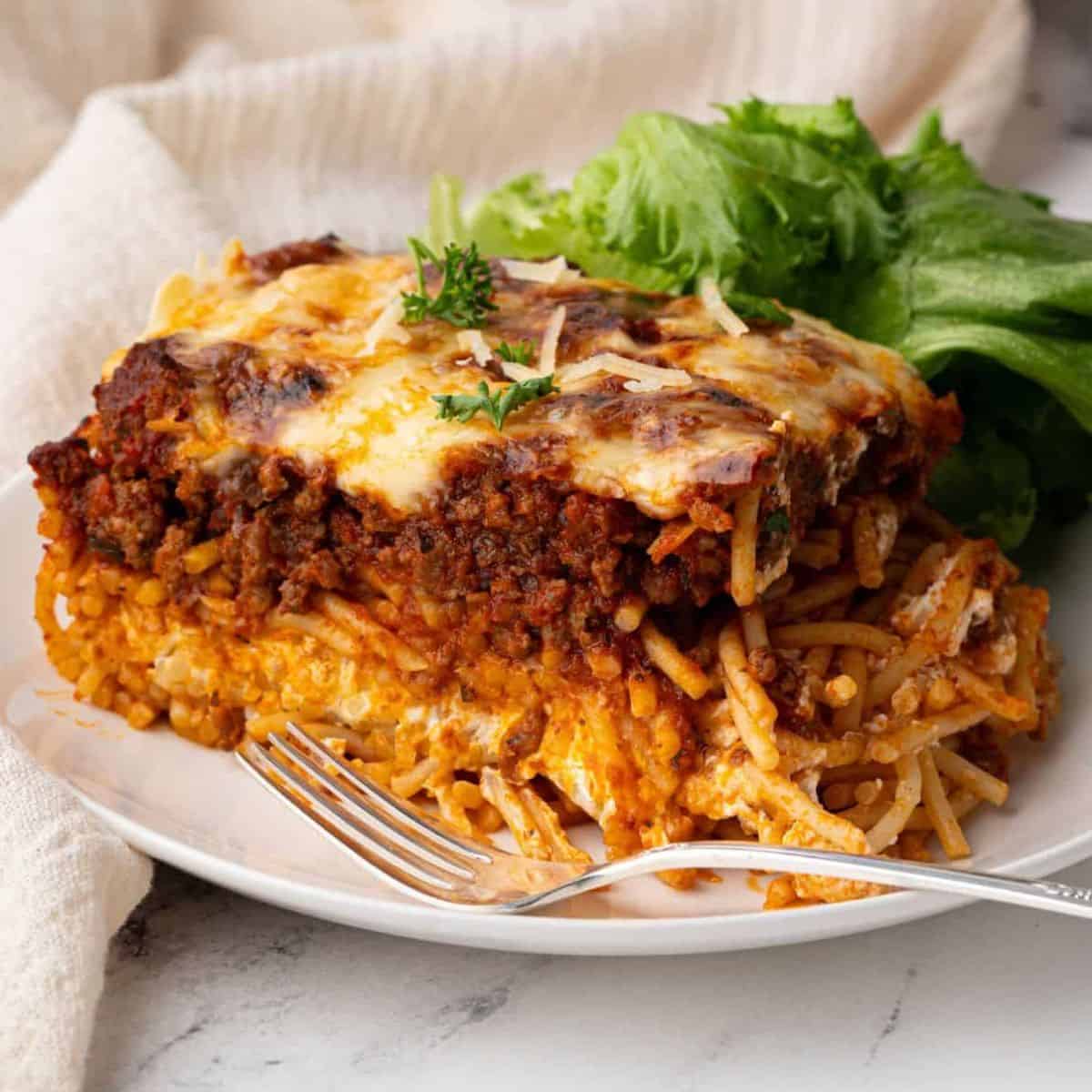 Million dollar spaghetti slice on a plate with greens