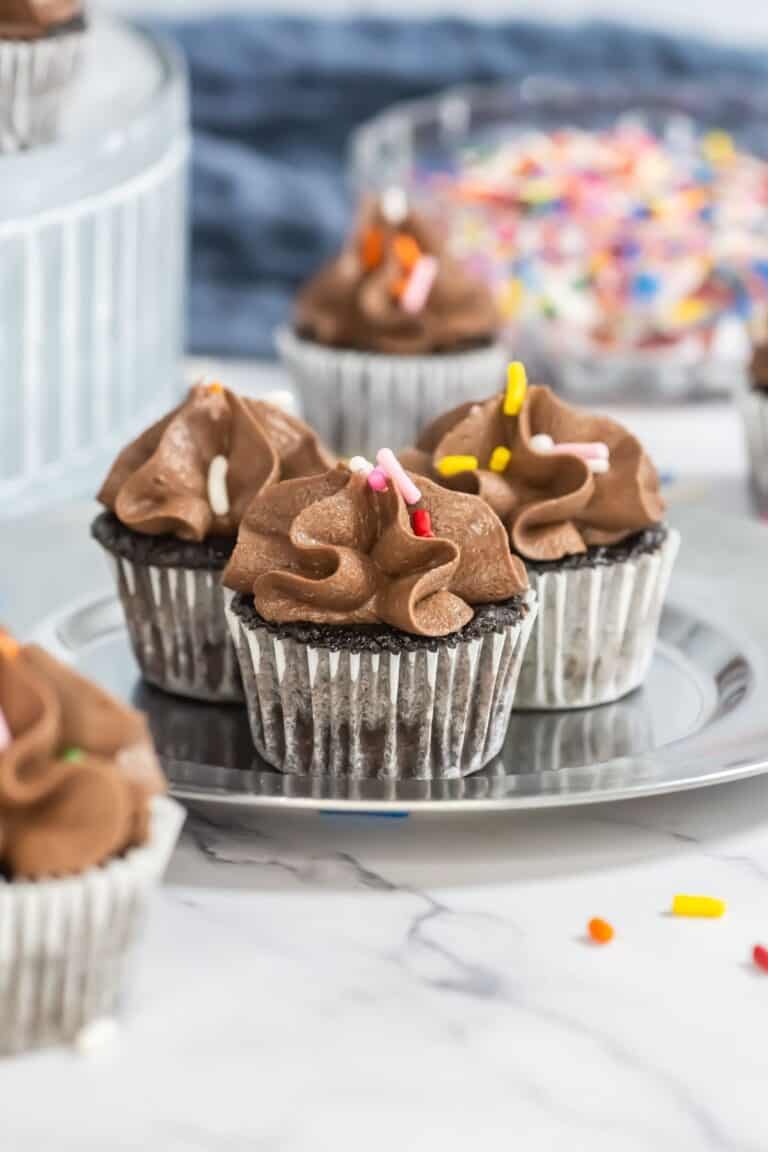small silver plate with 3 mini chocolate cupcakes with chocolate frosting and sprinkles