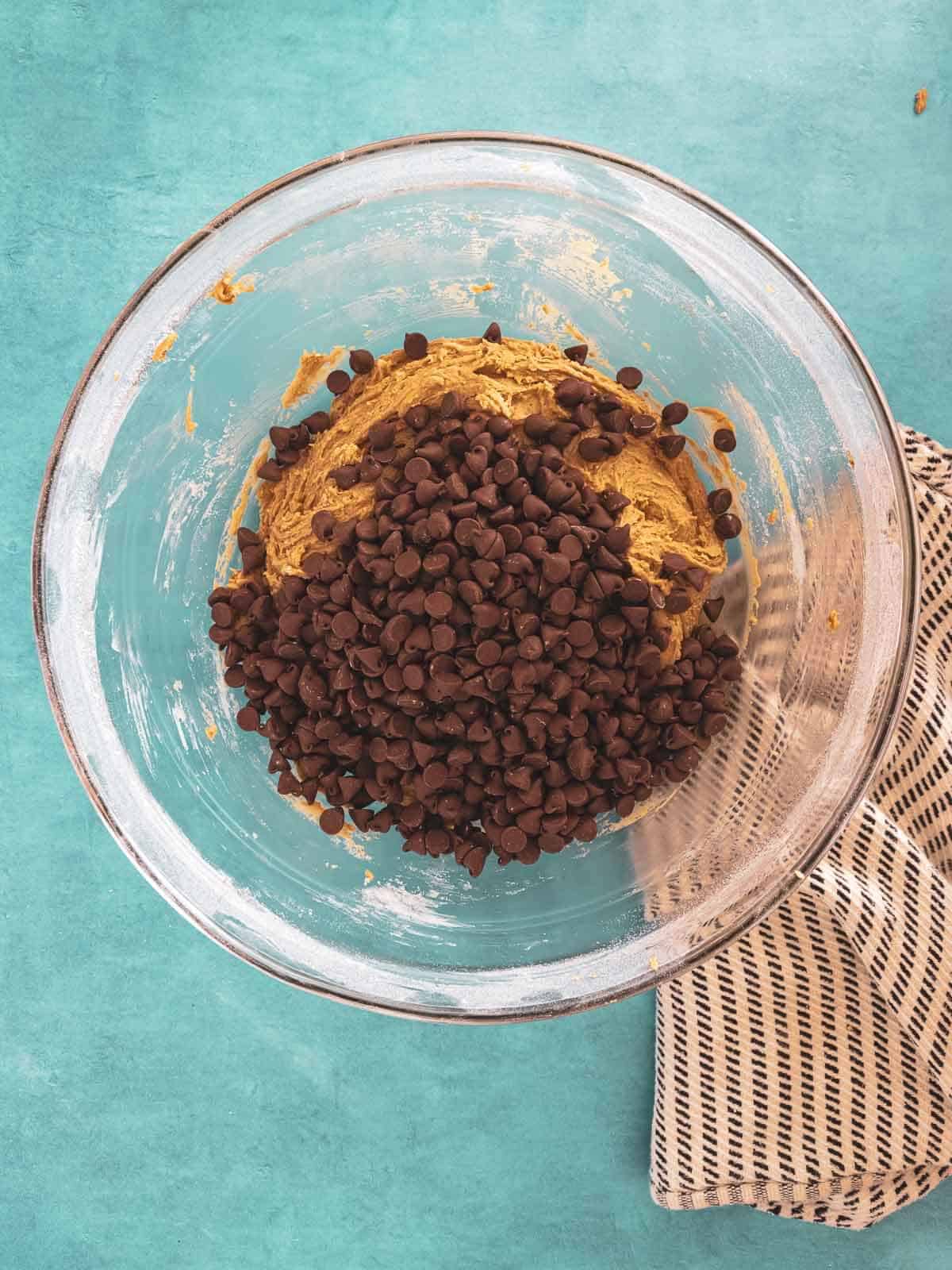 A heap of chocolate chips added to the cookie dough.