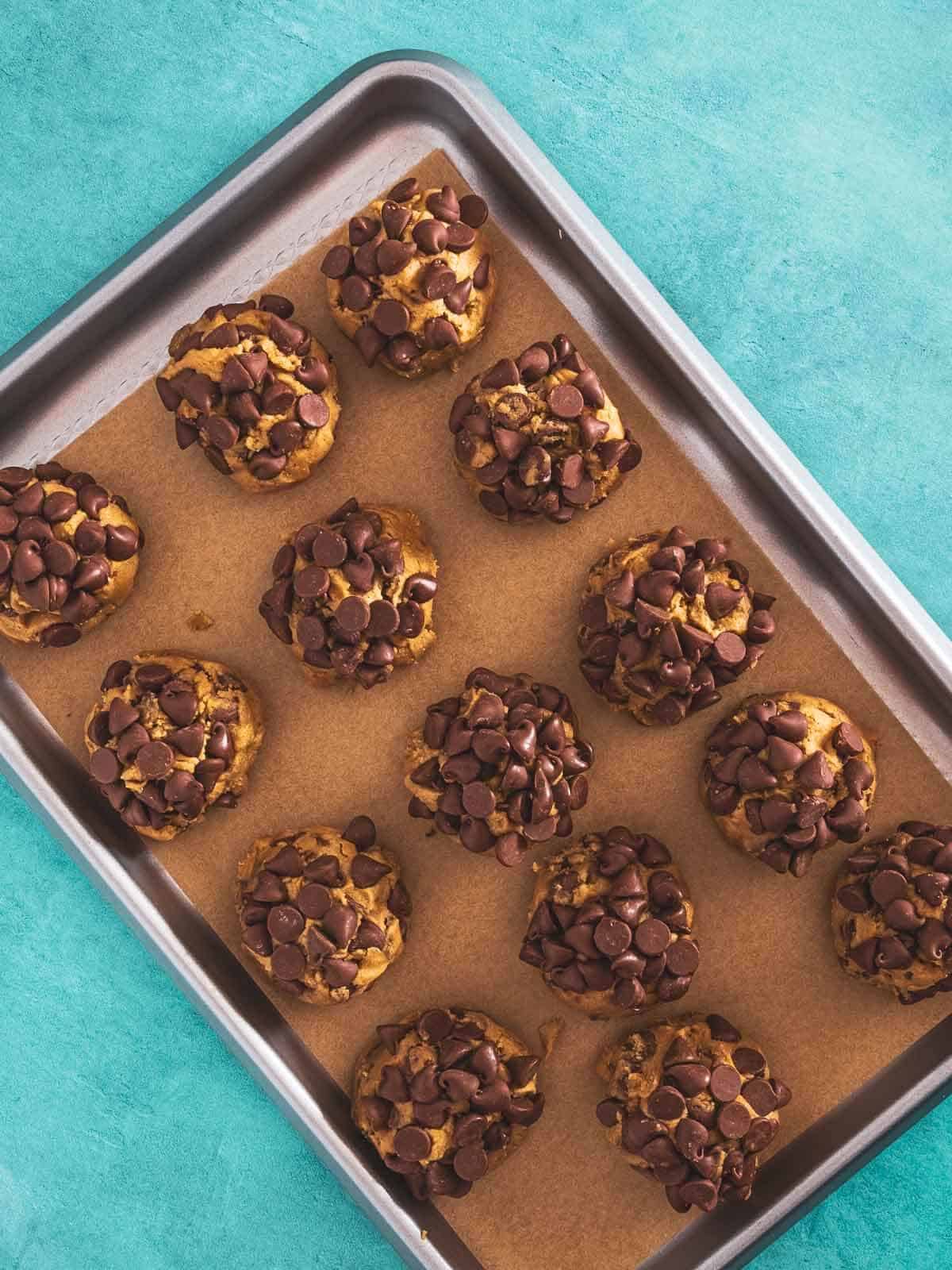 Cookie dough balls arranged on a baking sheet.