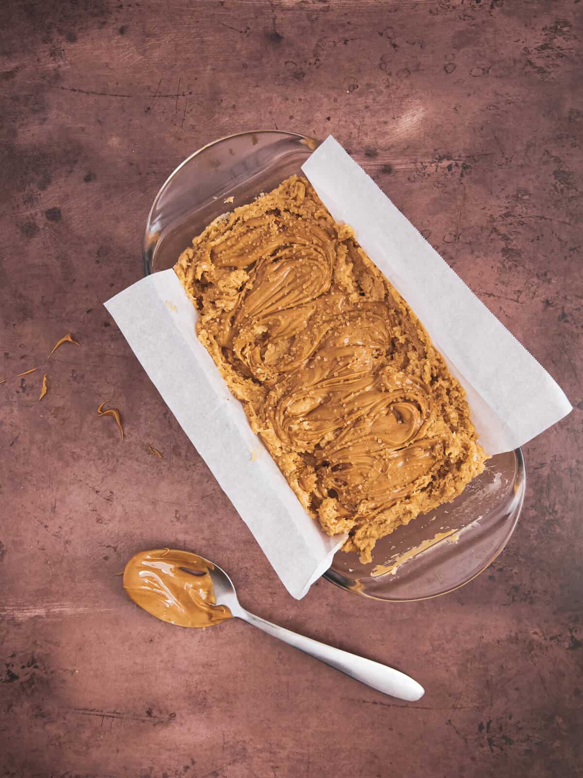 A close-up of the loaf pan filled with batter, with peanut butter swirled into the top before baking.