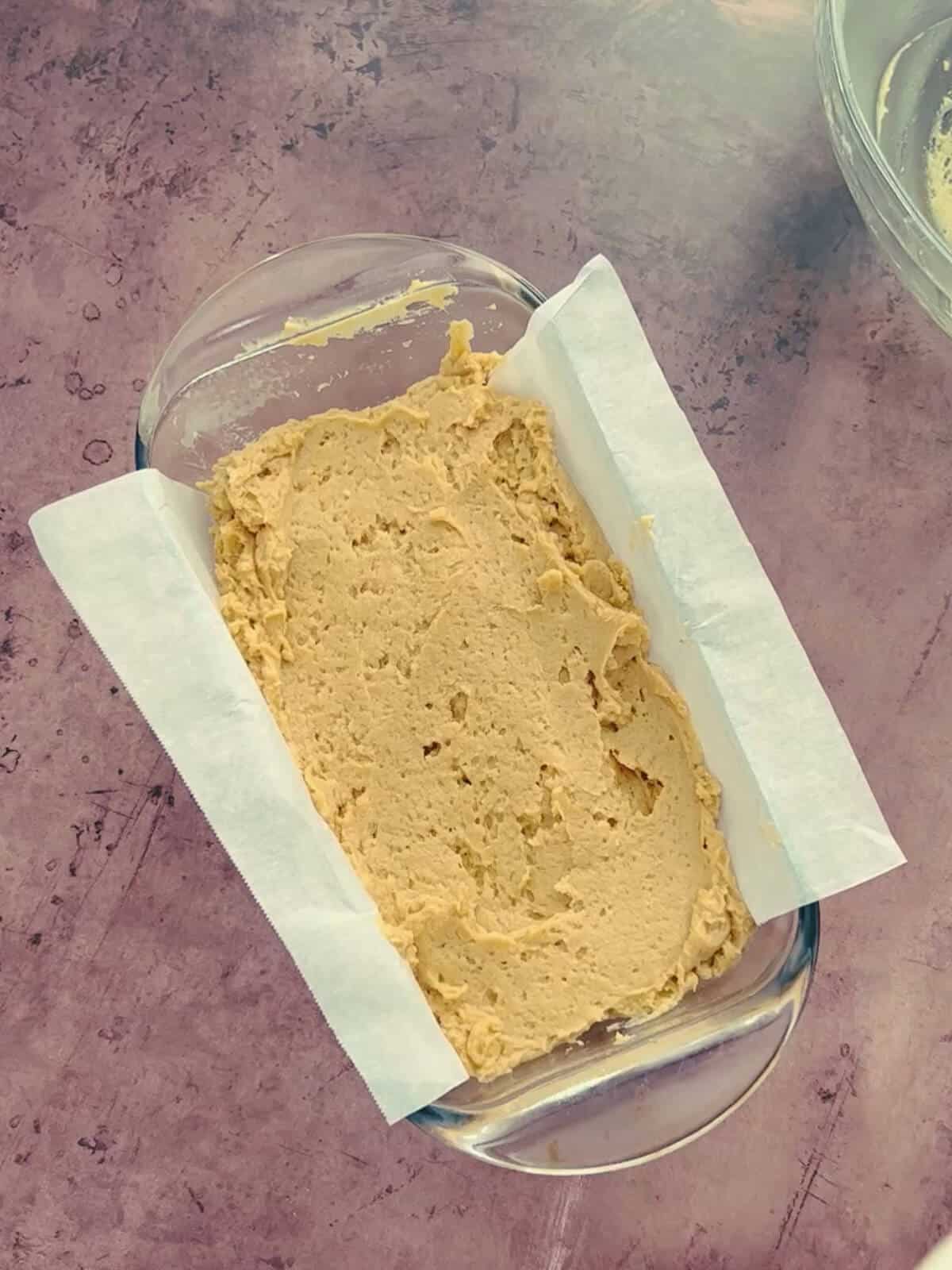 A parchment-lined loaf pan filled with peanut butter bread batter, prepped for baking.