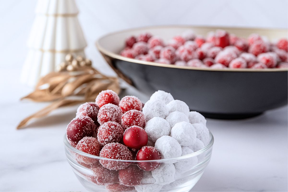 a bowl with half candied cranberries and half sugared cranberries on a marble countertop