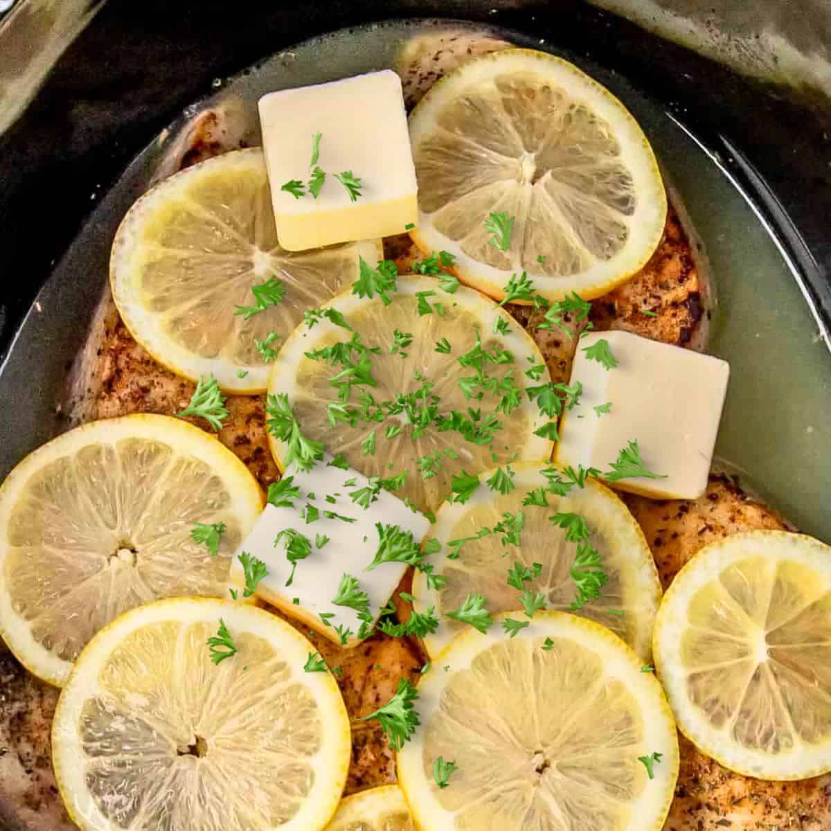 slow cooker lemon chicken seared chicken breasts in a crock pot with lemon wedges and butter