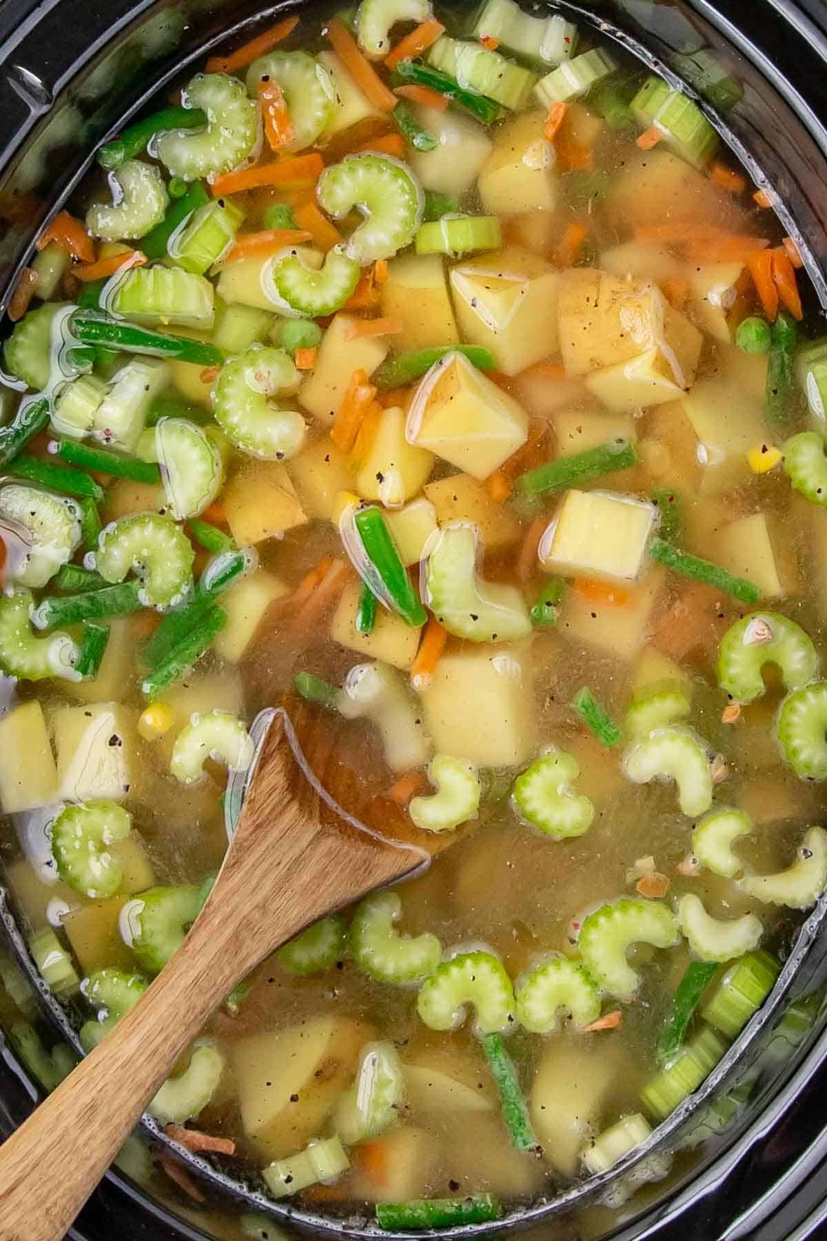 Shots of the stew cooking in the slow cooker, highlighting raw, colorful ingredients like celery, green beans, carrots, and potatoes submerged in broth.