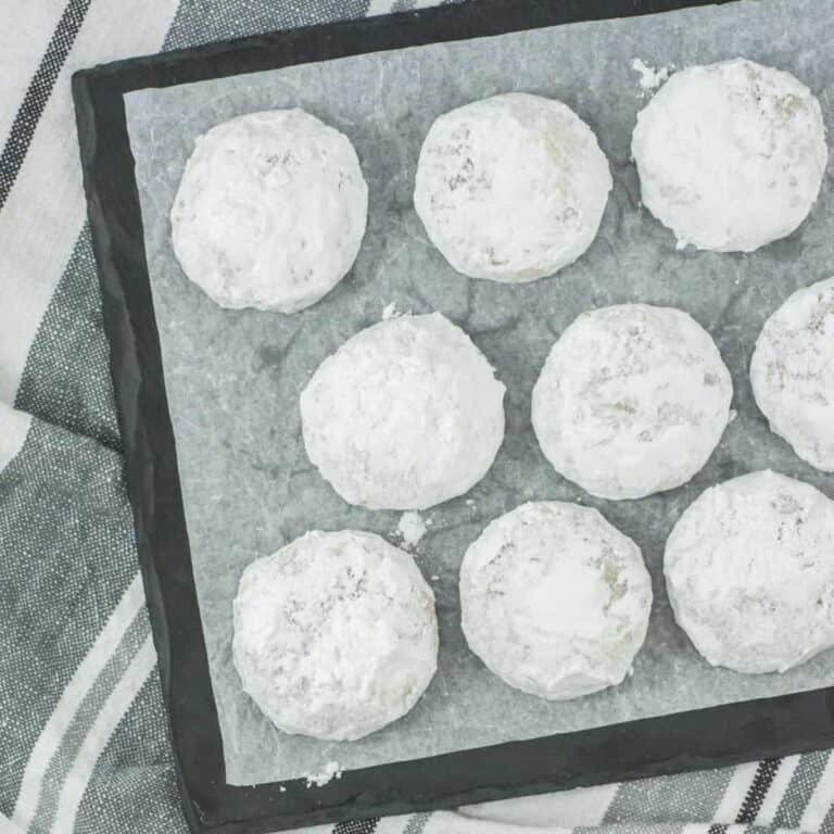 snowball cookies on a plate with parchment paper under them