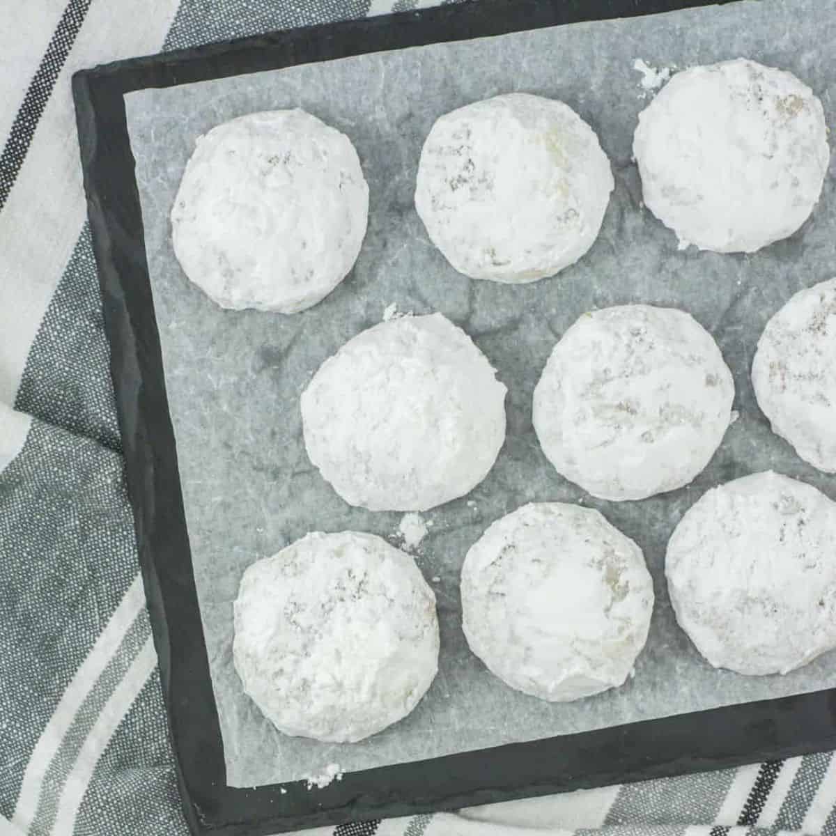 snowball cookies on a plate with parchment paper under them