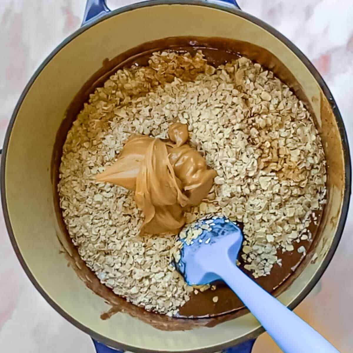 Oats and a large dollop of peanut butter being stirred into the hot chocolate mixture.