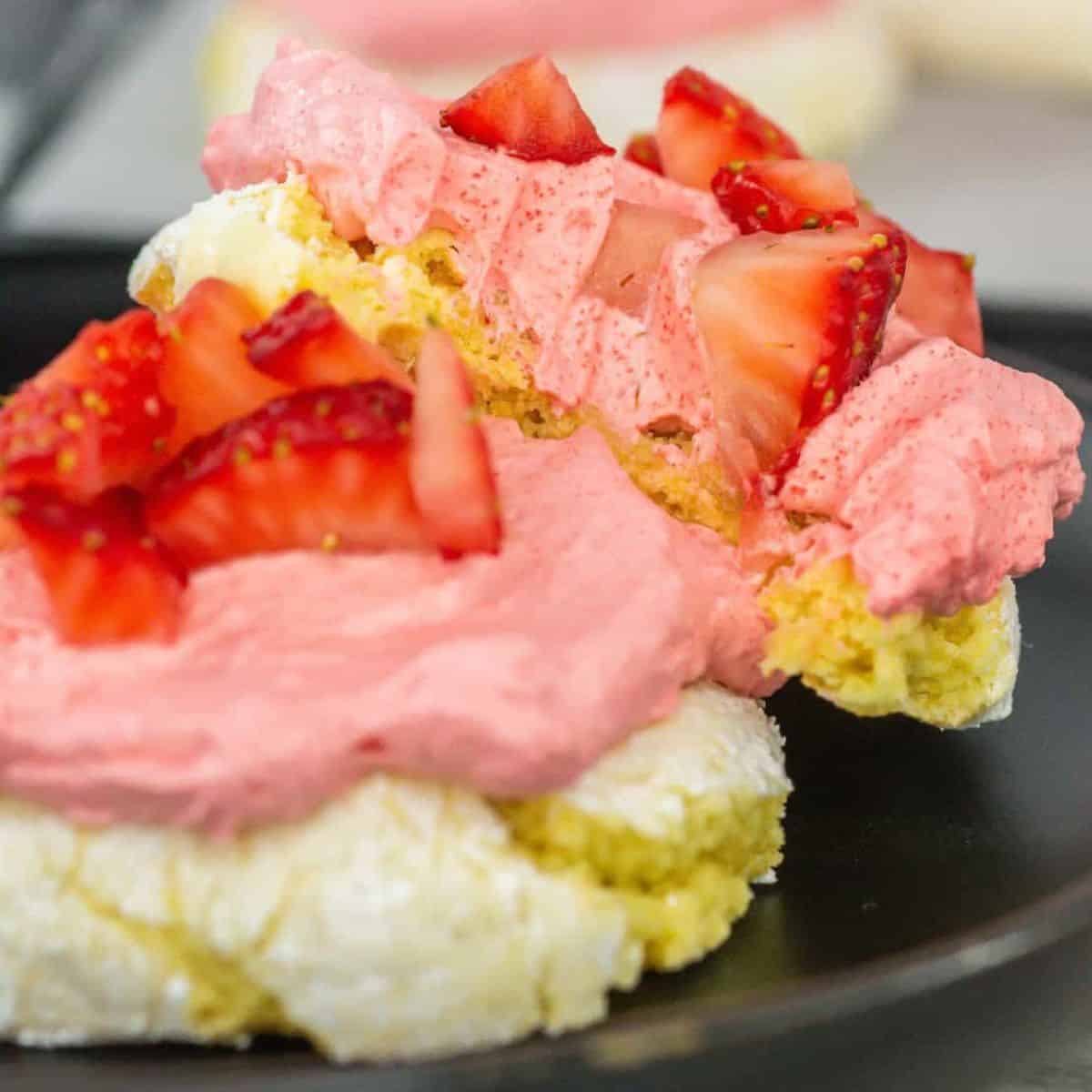Strawberry lemonade cookies with a lemon cookie base topped with a strawberry whipped cream frosting and fresh strawberries