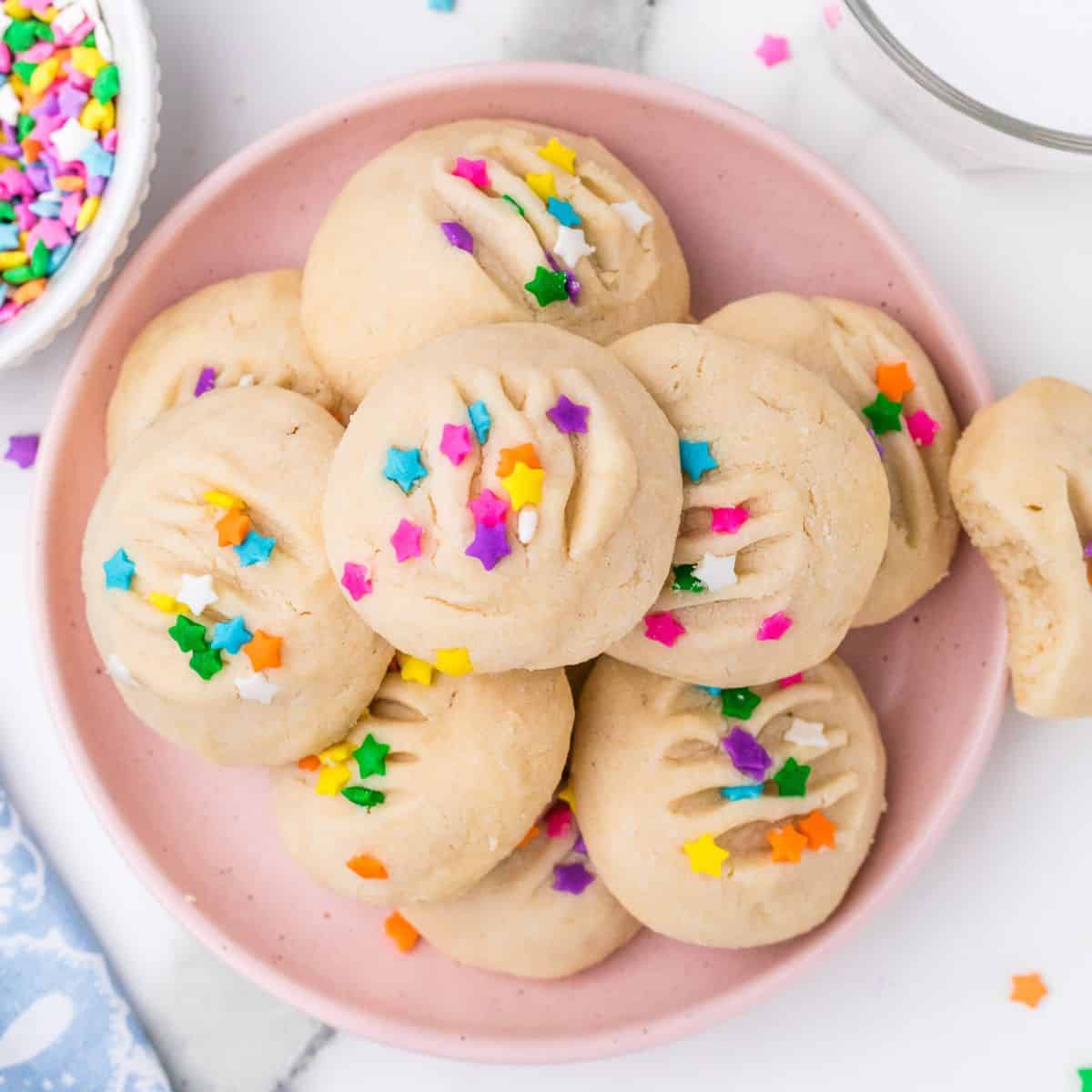 whipped shortbread cookies stacked on a pink plate