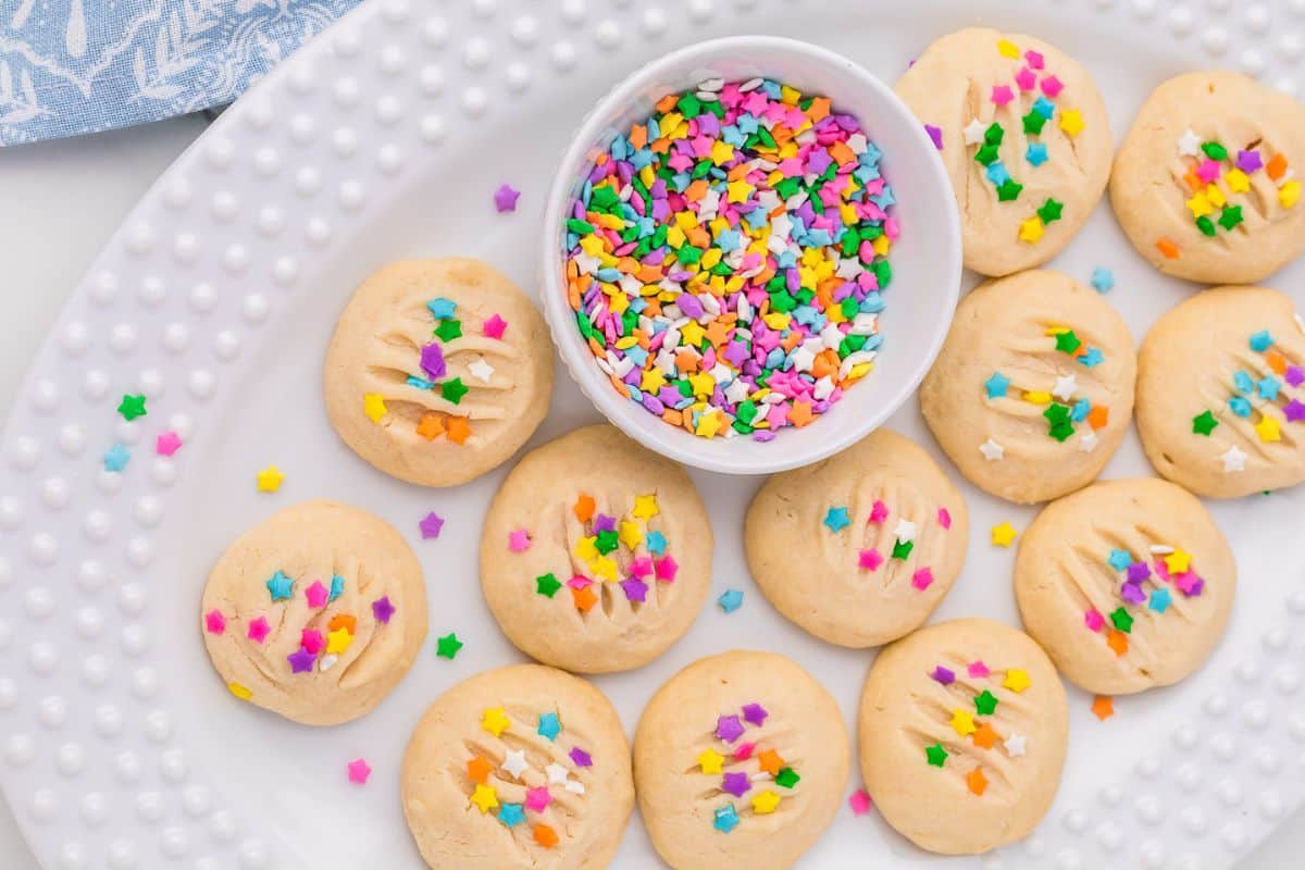 A plate of whipped shortbread cookies with sprinkles