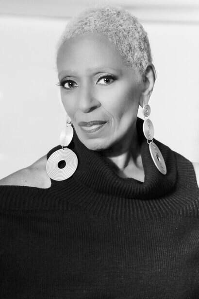 Short, stylish portrait of an elegant woman with short gray hair wearing statement earrings.