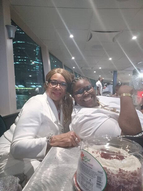 Elegant women enjoying dinner at a high-rise restaurant with city views at night.