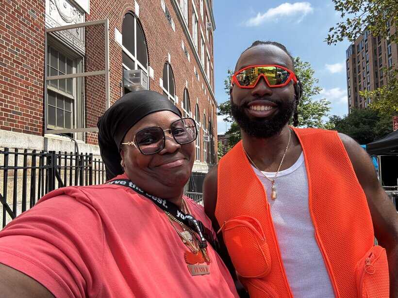 Vibrant outdoor street scene with smiling African American woman and man in safety vests and sunglasses, urban background.