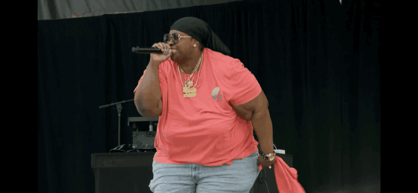 Performer singing with microphone on stage at UOhnIt.com event in stylish casual outfit.