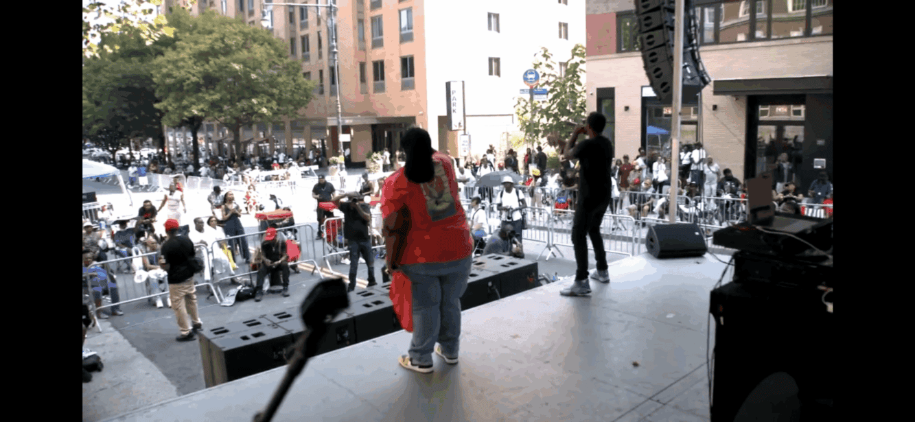 Music event with performers on stage and audience in urban outdoor setting, city square, lively atmosphere, concerts and public entertainment, UOhnIt.com.