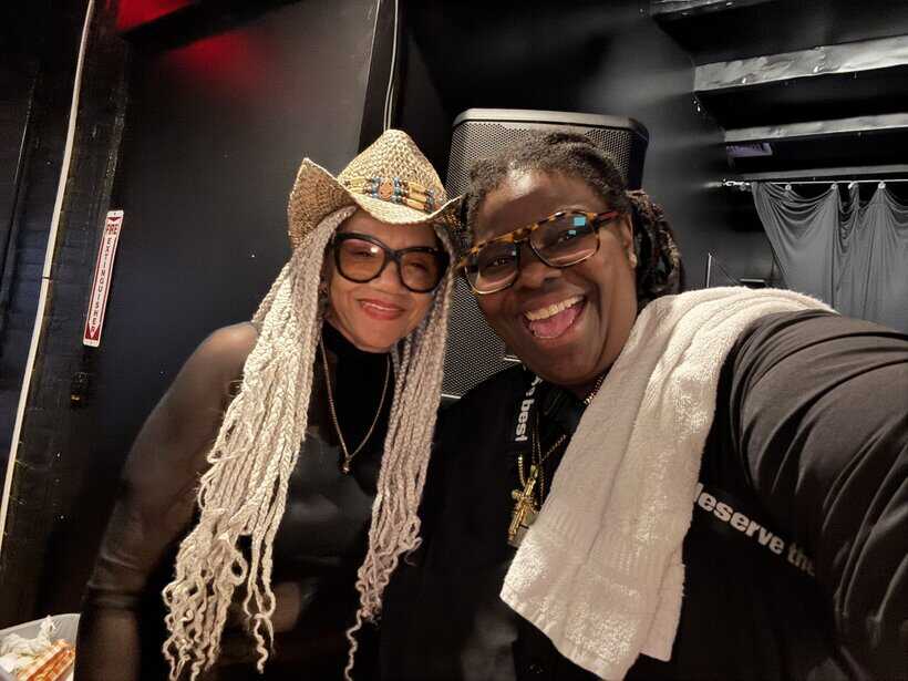 Striking African American man and woman smiling, taking a selfie at a music event or party.