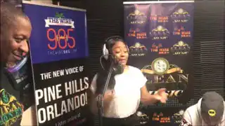 High school girl recording podcast in studio with banners and equipment.