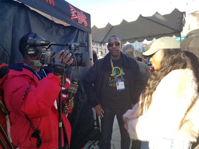 Interviewing at a busy outdoor event, capturing moments of media coverage and networking.