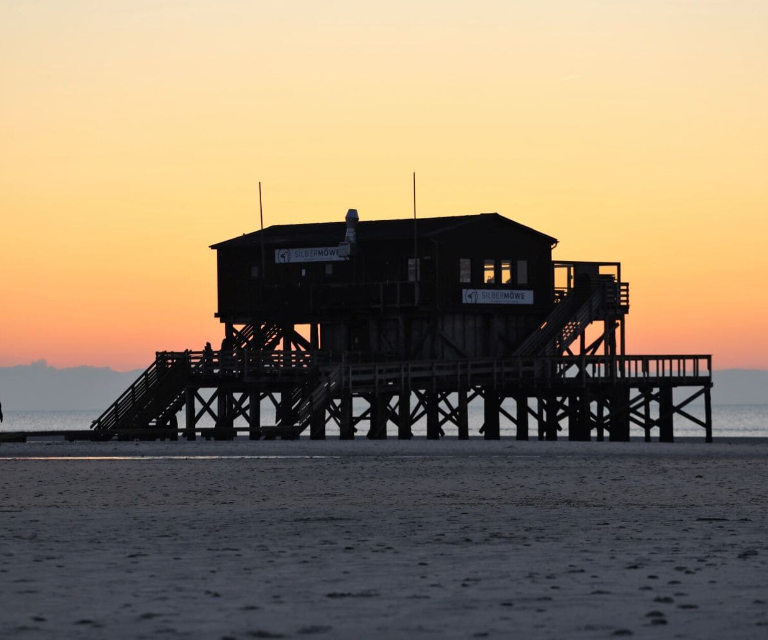 Ein Paar geht zu einem Pfahlbaurestaurant im Sonnenuntergang.