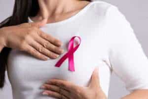 Woman with pink ribbon on chest, symbol of breast cancer awareness and reconstruction.