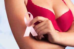 Woman holding pink ribbon symbol for breast cancer awareness, promoting reconstruction options.