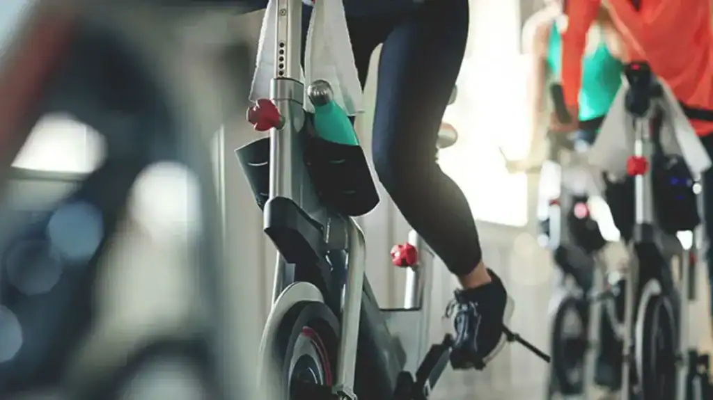 Kobieta ćwicząca na rowerze stacjonarnym, promująca fitness i turystykę zdrowotną w Albanii.