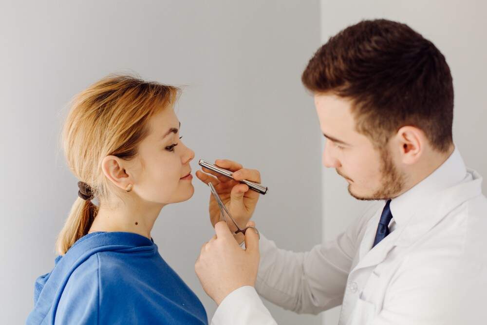 Arzt untersucht die Nase eines Patienten zur Korrektur einer knolligen Nasenspitze in Albanien.