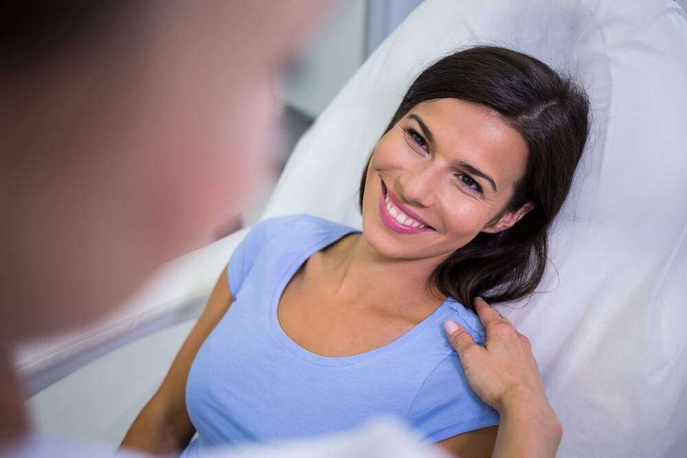 Woman smiling after liposuction consultation in Albania.