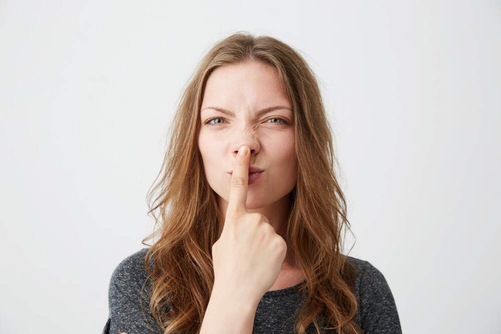 Frau hält einen Finger an die Nase, was auf eine kugelförmige Nasenspitze hinweist.