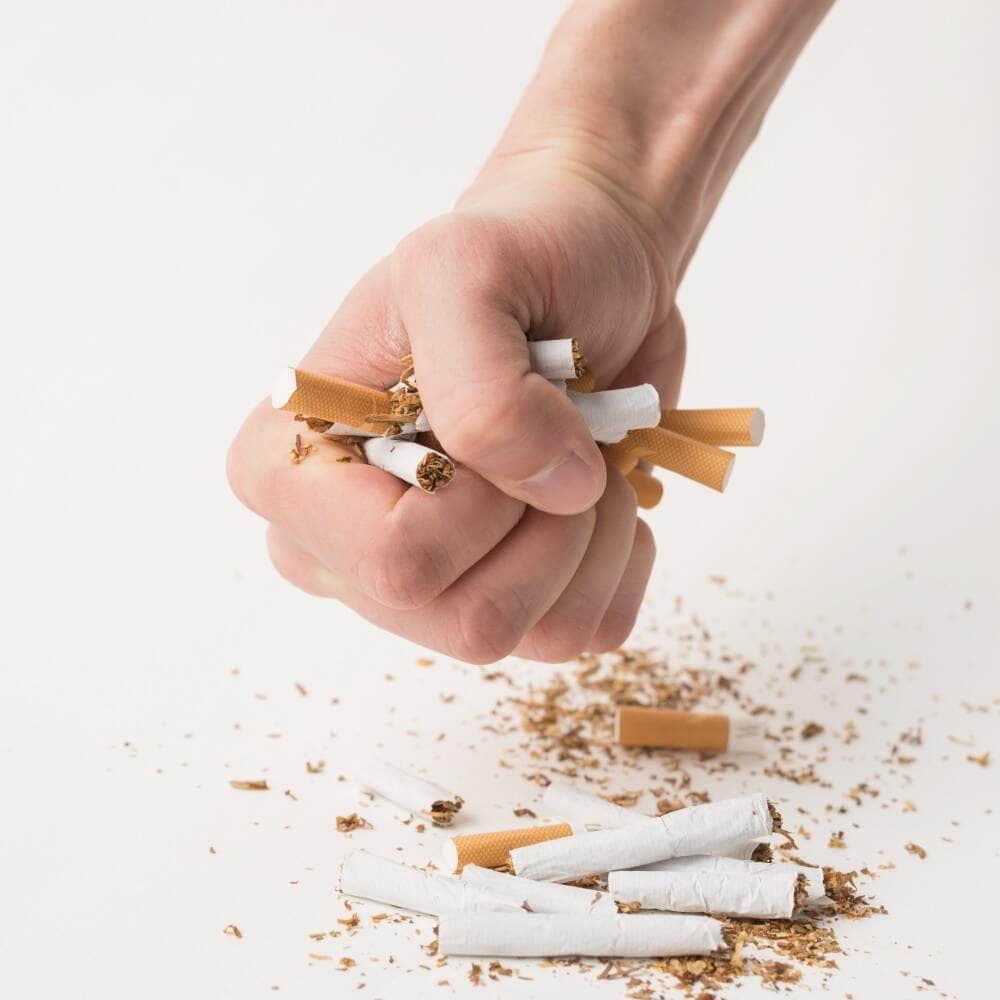 Des mains écrasant des cigarettes pour promouvoir l'arrêt du tabac en Albanie.
