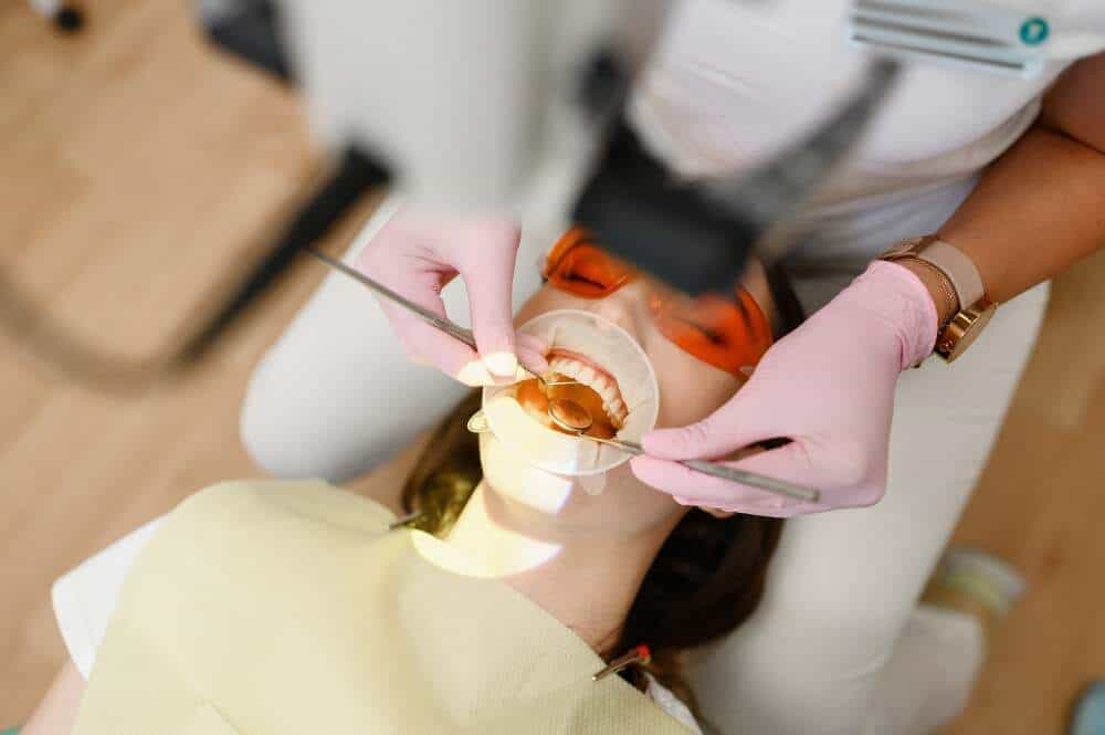 Dentist duke ekzaminuar dhëmbët e pacientit për trajtimin e abscesit në Shqipëri.