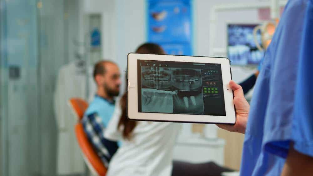 Dentista che esamina immagini radiografiche digitali dentali su un tablet in clinica.