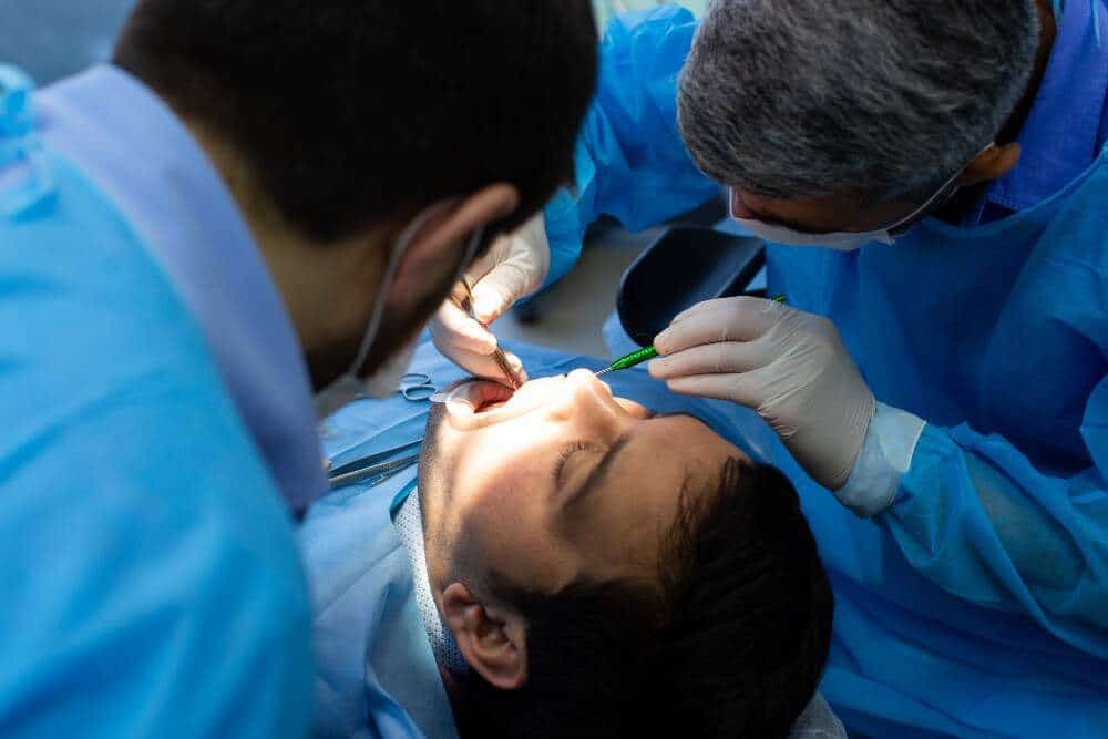 Dentista colocando un implante dental a un paciente durante un procedimiento de turismo médico en Albania.