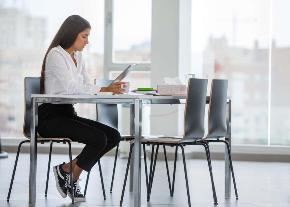 Modern woman reading document at a table in a bright office.