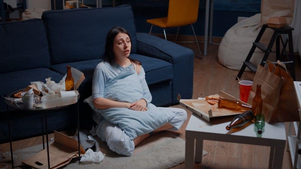 Woman sitting on sofa after butt lift procedure in Albania.