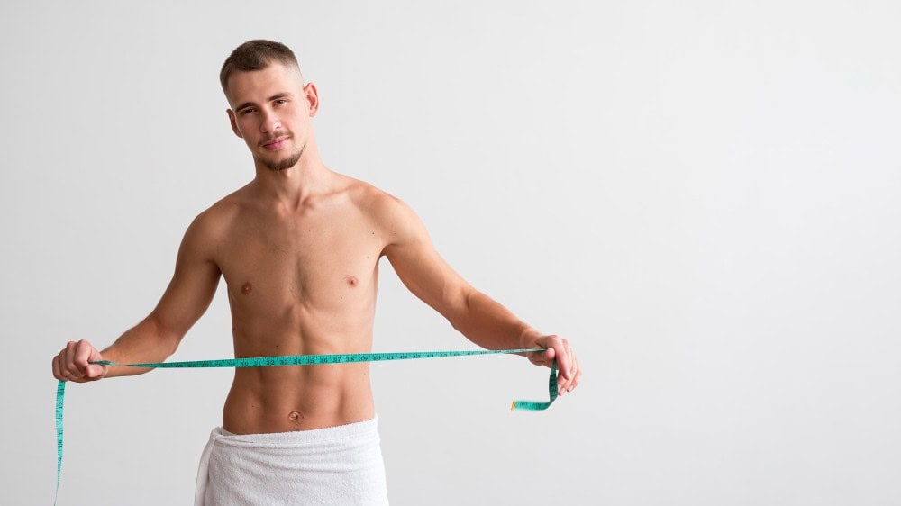Confident man with measuring tape, symbolizing body enhancement and cosmetic surgery in Albania.